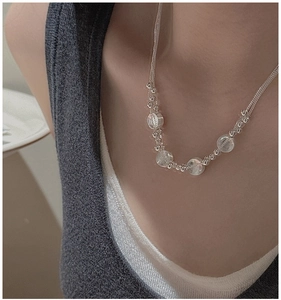 Macro shot of layered S925 sterling silver chain with translucent beads on model
