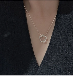 Detail of S925 silver hollow flower pendant on beaded chain worn by a female model