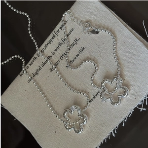 Detail of S925 silver necklace featuring two hollow flower charms on a beaded chain