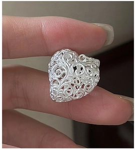 Close-up of vintage S925 sterling silver heart pendant with intricate hollow filigree patterns