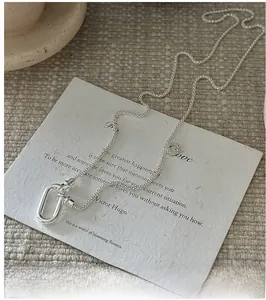 Détail du collier chaîne serpent en argent S925 avec boucle ovale sur tissu beige