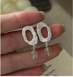 Detail of matte S925 silver earrings with organic hammered texture and yellow crystal beads