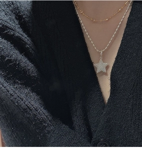 Detail of layered gold bead chain and silver rope chain with shiny star pendant