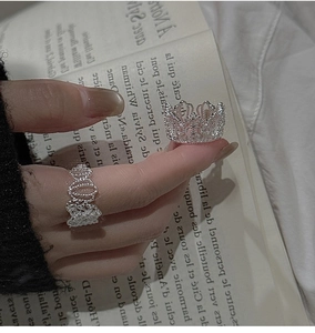 Dettaglio dei due anelli in argento 925 con corona e pizzo su un libro vintage