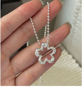 Macro shot of silver flower pendant with lava texture on minimalist ball chain necklace