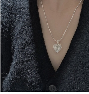 Detail of 925 sterling silver hollow heart pendant on a black knit cardigan