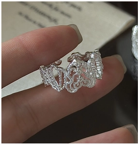 Dettaglio anello in argento con motivo pizzo e trama filigrana su sfondo di un libro
