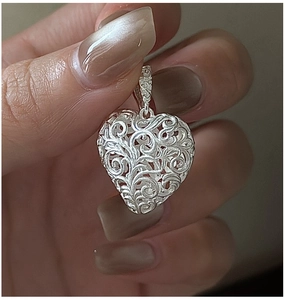 Macro detail showing vintage S925 silver hollow heart pendant with intricate texture