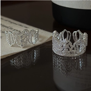 Dettaglio di anelli in pizzo argento con motivi a cuore e design a corona con zirconi