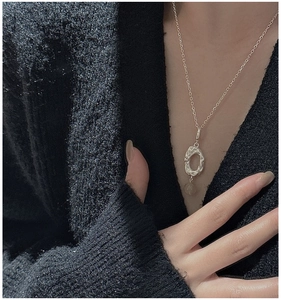 Detail of silver necklace with hammered oval pendant and pale translucent gemstone bead