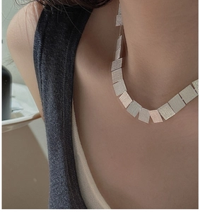 Detail of minimalist silver necklace with brushed rectangular metal links on neck