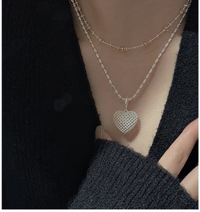 Detail of 3D hollow mesh heart pendant with double-layered silver chain on a model