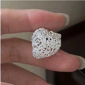 Macro detail of a vintage S925 sterling silver heart pendant with floral cut-out patterns