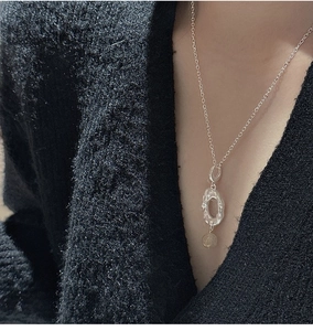 Detail of S925 silver necklace with textured oval pendant worn on a black cardigan