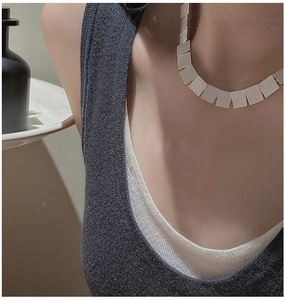 Detailed view of silver minimalist necklace featuring textured square metallic flakes