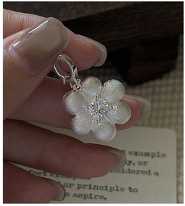 Macro shot of S925 silver flower pendant with brushed metal petals and a clear center stone