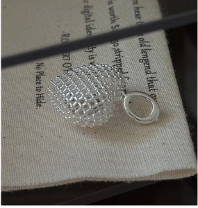 Macro view of a 3D hollow mesh heart pendant in S925 sterling silver on canvas