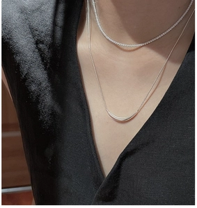 Détail de colliers superposés en argent S925 avec chaîne serpent et pendentif poli