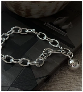 Detailed close-up of textured silver chain links with a polished mirror ball pendant