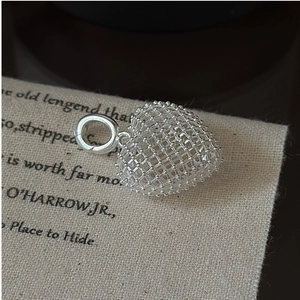 Macro shot of 3D hollow mesh heart pendant with bead details on vintage paper backdrop