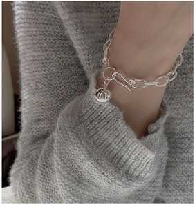 Detail of a 925 sterling silver beaded bracelet with S-hook clasp on a knit sweater