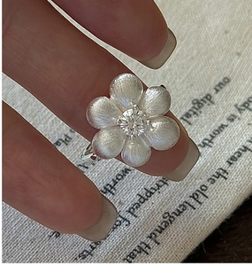Detail of S925 sterling silver flower ring with brushed texture and sparkling gemstone