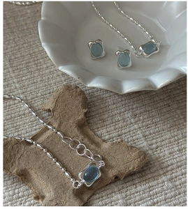 Detailed close-up of light blue gemstone jewelry set with silver bead chain texture