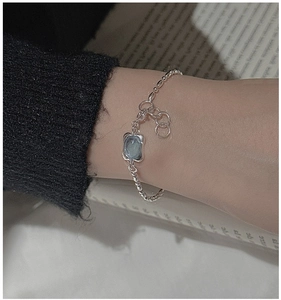 Detail of silver beaded bracelet featuring a pale blue oval gemstone on woman wrist