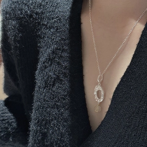Artistic S925 sterling silver necklace with textured oval pendant on black knitwear