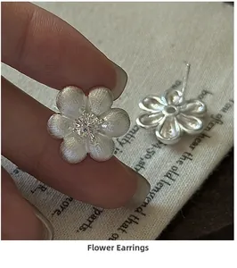 Vue détaillée des boucles d'oreilles fleurs en argent S925 avec texture brossée et zircon