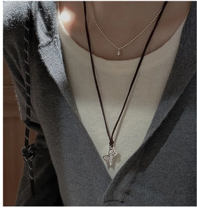 Detail view of layered S925 silver horse pendant and minimalist droplet charm necklace