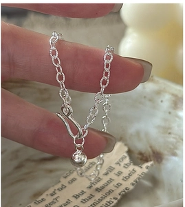 Macro shot of silver link bracelet with spherical pendant and buckle closure detail