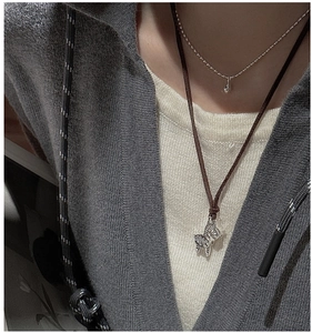 Close-up of a silver zebra pendant and water drop necklace on a grey sweater