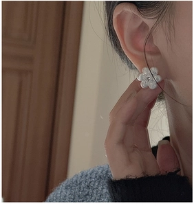 Gros plan sur une boucle d'oreille fleur en argent S925 brossé avec un zircon central