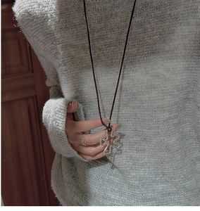 Detail of silver irregular flower pendant on long leather cord over grey knit sweater