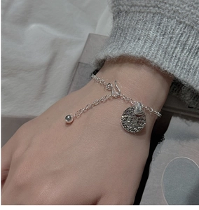 Close-up of S925 sterling silver bracelet featuring a hammered round pendant on model wrist