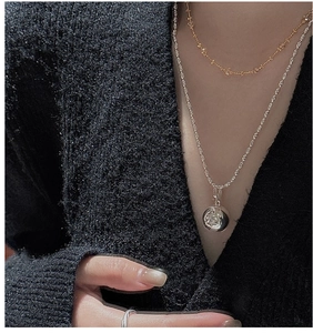 Detail of layered gold bead chain and silver necklace with engraved star sphere pendant