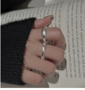 Detail of irregular wave silver ring with polished finish on finger and French book background