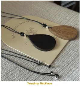 Close-up of wood grain teardrop pendants on black wax cord with silver bead accents