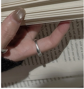 Detail of minimalist S925 silver irregular twisted ring on hand with vintage book background