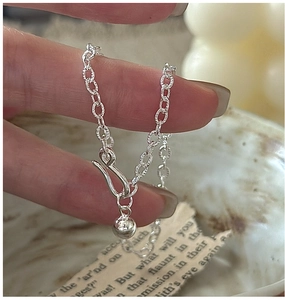 Detail of silver chain bracelet featuring a unique buckle clasp and polished ball pendant