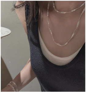 Detailed view of layered S925 silver necklaces with textured metal ripple effect on model