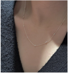 Détail d'un collier chaîne bambou doré élégant porté avec un haut à col en V