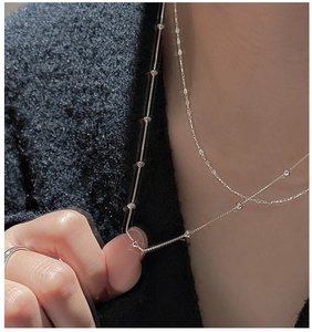 Detail of layered S925 silver box chain necklace and matching minimalist band ring on model