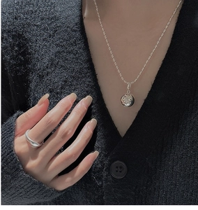 Detail of S925 silver necklace with star ball pendant and irregular ring on a model