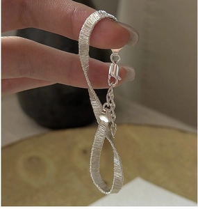 Detail of woven S925 sterling silver bracelet with lobster clasp and heart pendant