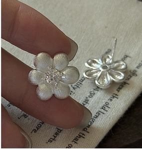 Détail macro de boucles d'oreilles fleurs en argent S925 avec texture brossée et zircon