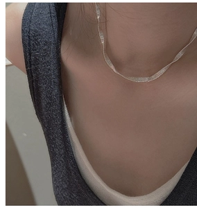 Macro shot of silver flat snake chain necklace with fine textured shimmer finish