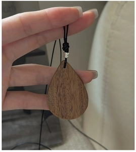 Close-up of teardrop walnut wood pendant with natural grain and silver bead detail