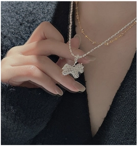 Close-up of a textured silver terrier dog pendant on a beaded chain for layered styling